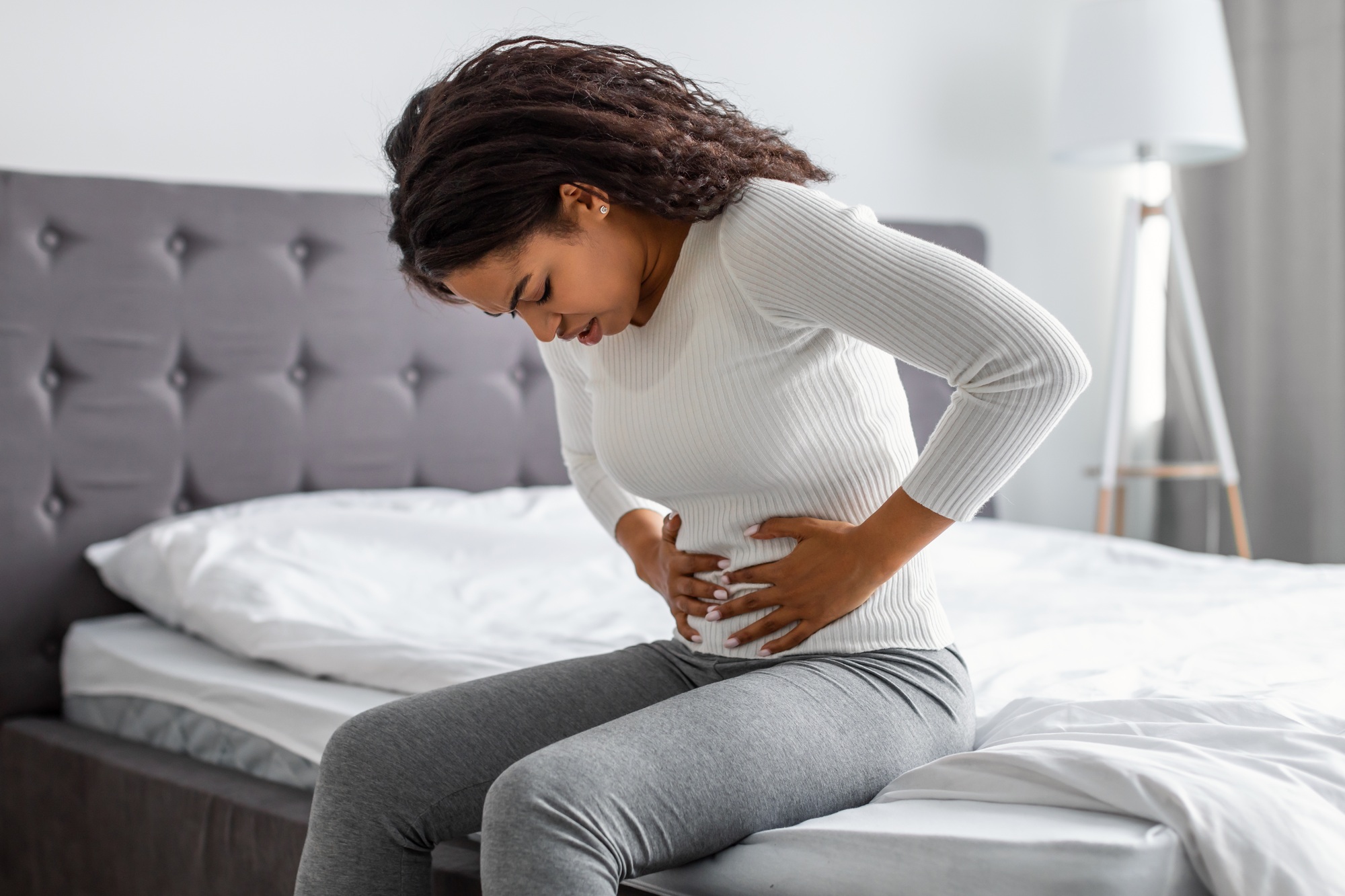 Black woman suffering from stomachache, touching her tummy